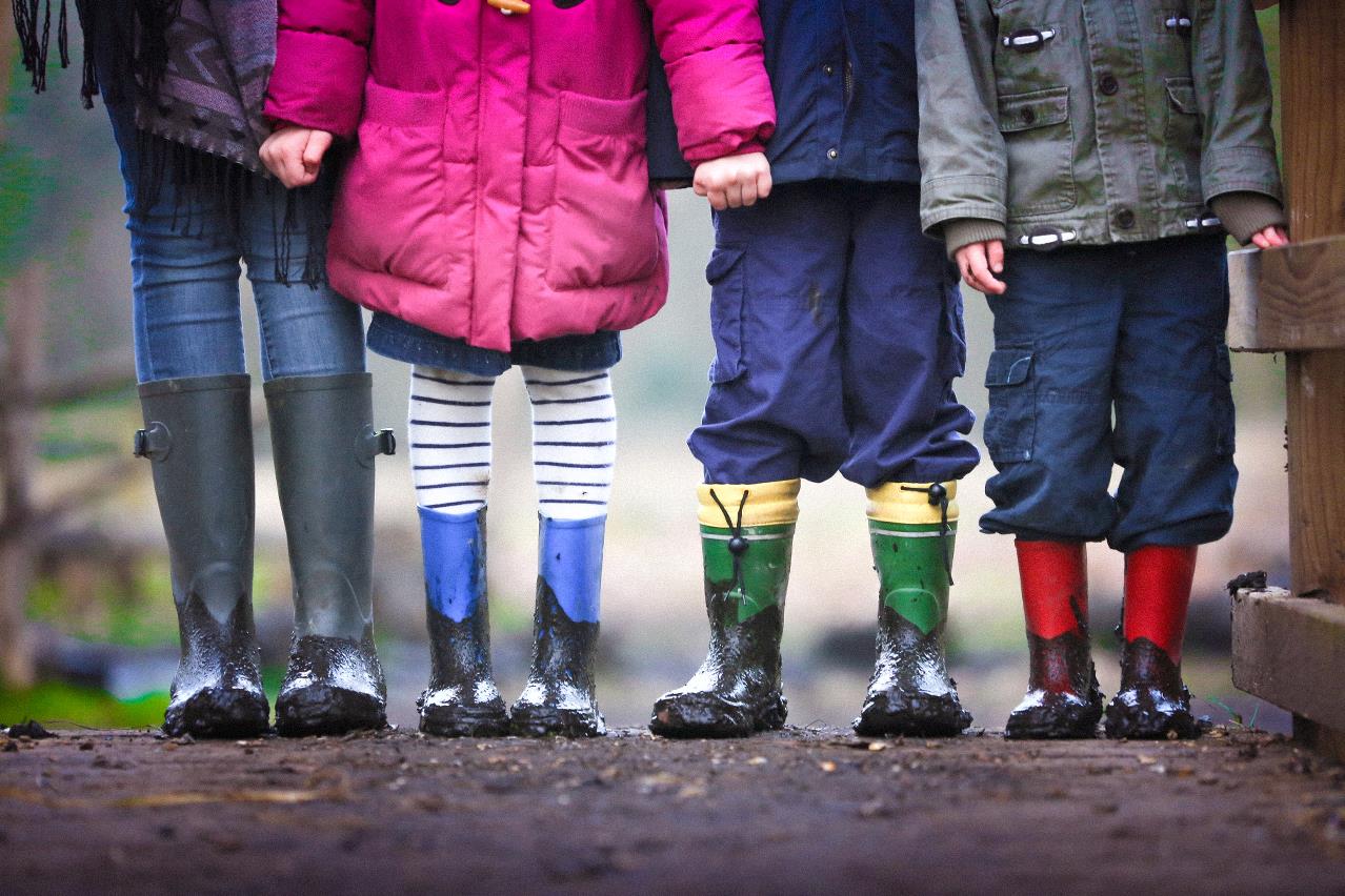 Fire børn i forskellig farvede gummistøvler